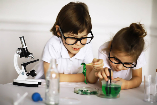 Duas crianças bonitas na aula de química fazendo experimentos isolados no backgroun branco - Foto, Imagem