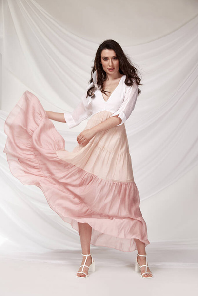 Beautiful sexy woman wear light pink multicolor dress summer collection silk casual style tanned body brunette hair beautiful face makeup white background studio. - Foto, Imagem