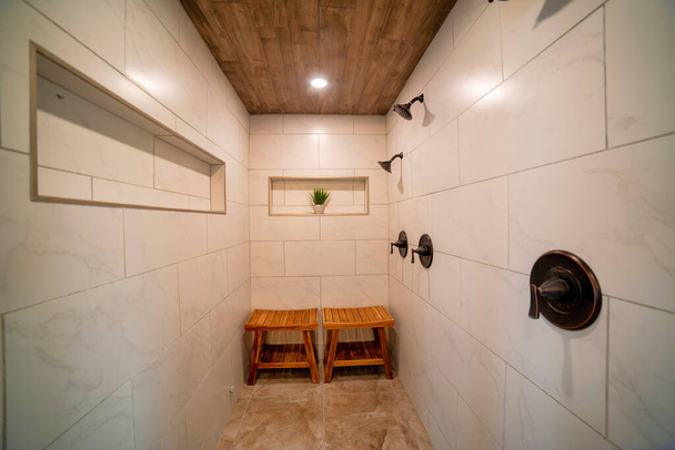 a bathroom with tile on the walls, wooden celling and two small chairs - Foto, Bild