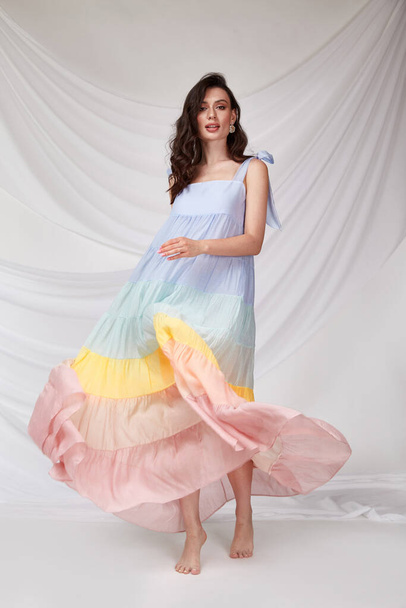 Beautiful sexy woman wear light multicolor silk dress summer collection party casual style tanned body brunette hair beautiful face makeup white background studio. - 写真・画像
