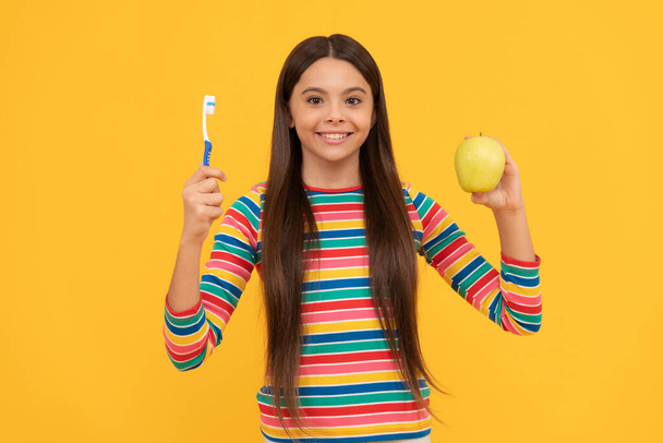 Siga la higiene bucal. Chica feliz sostén manzana y cepillo de dientes. Higiene oral. Cuidado dental - Foto, Imagen