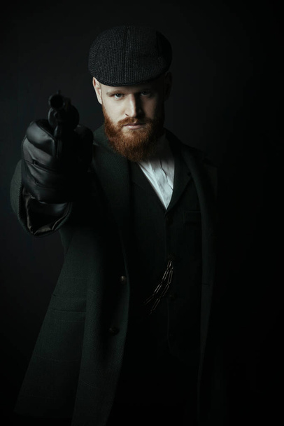 Victorian man wearing a tweed suit and flat cap holding a gun - Foto, imagen