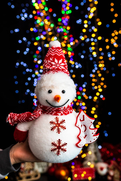 Holding Christmas decoration against bokeh lights background - Photo, Image