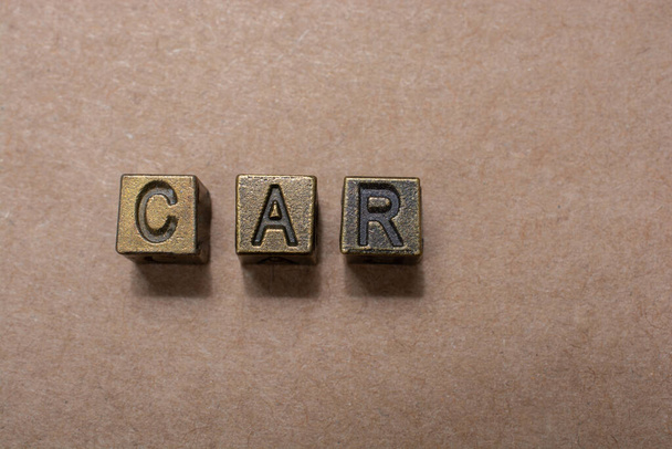 A top view of a word 'car' made with metal blocks isolated on a brown background - Valokuva, kuva