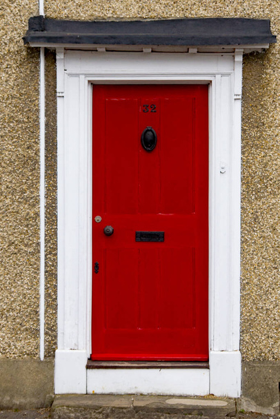 A 32-es számú ház egy piros fából festett ajtókereten Hertfordshire-ben, rézajtós kopogtatóval, és egy postaláda fogantyúval.. - Fotó, kép