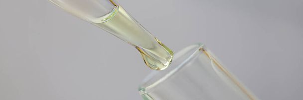 White-golden liquid is dripped from pipette into test tube - 写真・画像