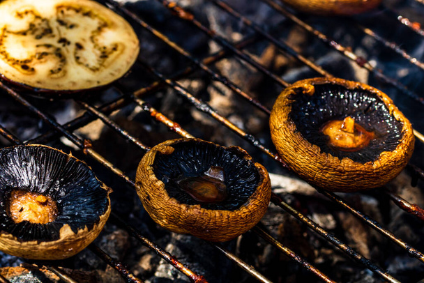 Tasty champignon  mushrooms and veggies being cooked on charcoal grill - Foto, imagen