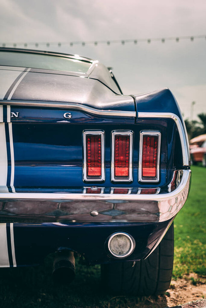 SHARJAH, UNITED ARAB EMIRATES - May 10, 2021: A vertical shot of tail lights on a Ford Mustang Vintage model car - 写真・画像
