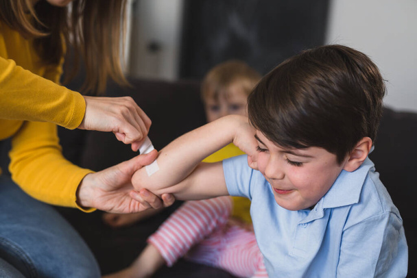 mother putting bandage on her sons elbow - Photo, image