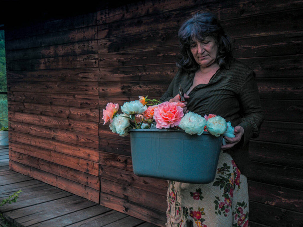 An Italian senior woman collecting flowers from her garden - Photo, Image