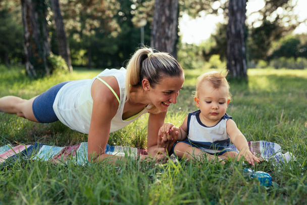 mother with her baby boy doing physical exercises outdoors - 写真・画像