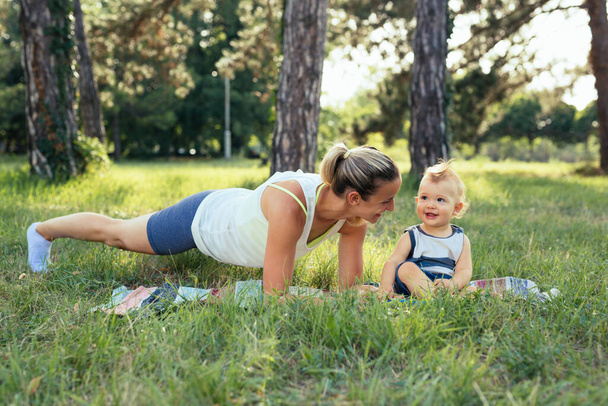 mother with her baby boy doing physical exercises outdoors - Photo, image