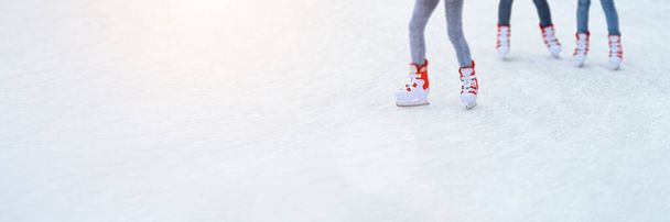 Jambes patinant sur glace. Longue bannière avec espace de copie. Les gens font du patin à glace dans des patins loués. Concept de sports d'hiver - Photo, image