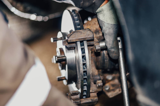installation of a new brake disc in a car, repair of a brake system in a car service. - Foto, imagen