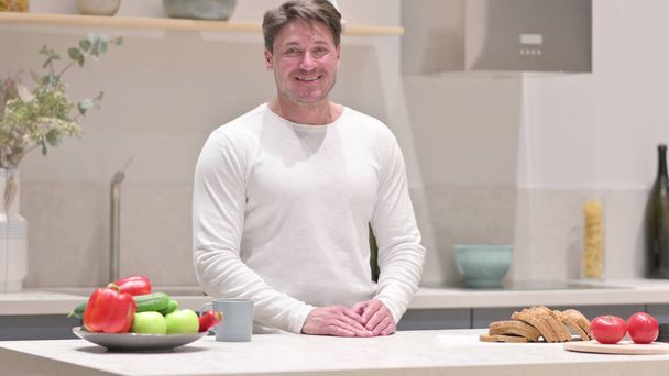 Middle Aged Man Smiling at the Camera while Standing in Kitchen - Photo, image