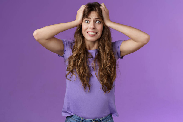 Girl feel panic troublesome perplexed situation clench teeth intense stare camera grab head distressed upset going insane crazy pissed popping eyes feel rage disappointment stand purple background - Photo, image