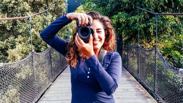 Bella donna è una fotografa professionista con una fotocamera DSLR nel parco. - Foto, immagini