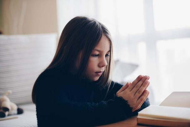 Dziewczyna modli się z rękami na Biblii. Koncepcja wiary i religii. - Zdjęcie, obraz