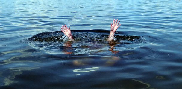Handen van een verdrinkende man boven water die hulp nodig heeft. - Foto, afbeelding