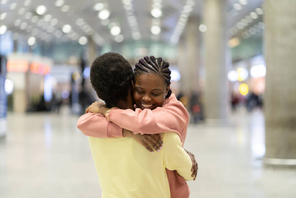 Family reunion in airport. Happy black male hugging excited woman after plane arrival in terminal - Foto, afbeelding