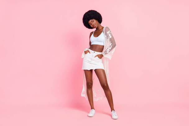 Full length photo of afro american charming lady hold hands pockets isolated on pastel pink color background - Foto, Imagem