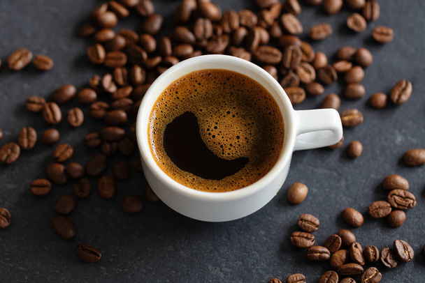 Steaming espresso cup on coffee beans background. Closeup  - Zdjęcie, obraz
