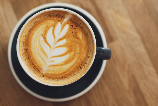 Tasty fresh cappuccino in cup on wooden table. Closeup - Фото, зображення