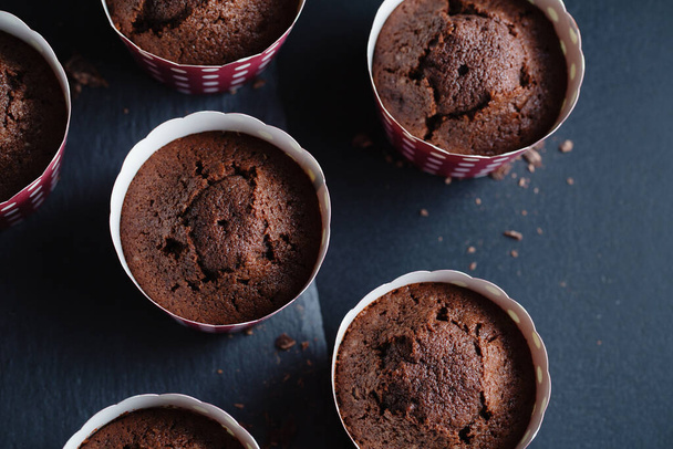Tasty appetizing chocolate muffins in cups on dark background.  - Foto, Imagem