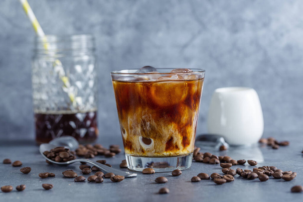 Tasty refreshing iced coffee with ice cubes in glasses on bright background. Closeup - Photo, Image