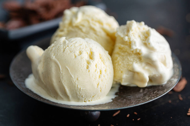 Vanilla ice cream scoops with chocolate chunks on dark plate. Closeup - Foto, imagen