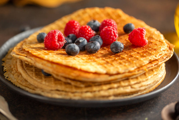 Golden crispy round waffles served on plate with berries. Closeup.  - Foto, Imagem