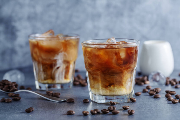 Tasty refreshing iced coffee with ice cubes in glasses on bright background. Closeup - Photo, Image