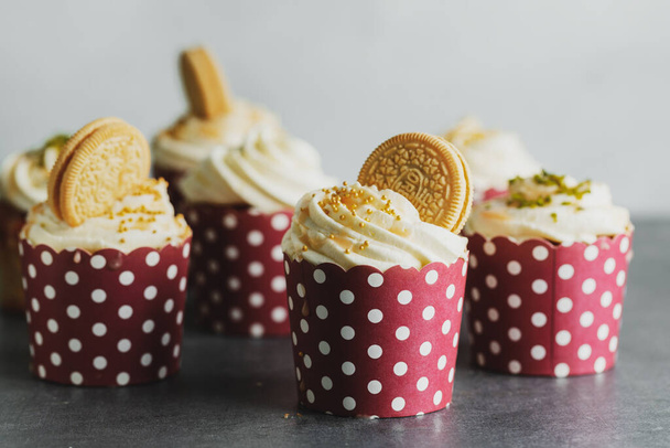 Vanilla cupcakes with cream and caramel on grey table background.  - 写真・画像
