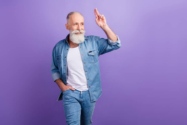 Photo of elderly man happy positive smile show fingers hello salute look empty space isolated over purple color background - Foto, Imagen