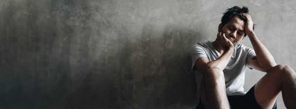 Depresivní a napjatý mladý Asiat sedí sám ve tmě na šedé zdi s kopírovacím prostorem, Životní problémy - Fotografie, Obrázek