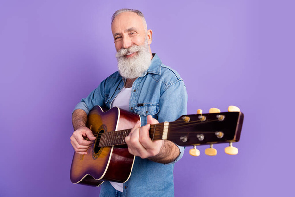 Profile side photo of aged man happy positive smile play guitar performance isolated over purple color background - Foto, imagen