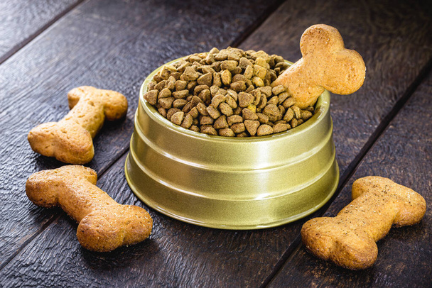 dog food with bone shaped dog biscuit in metallic bowl on wooden background, copy space - Photo, Image