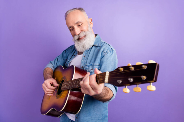 Profile side photo of aged man happy positive smile play guitar music lover isolated over purple color background - Foto, afbeelding