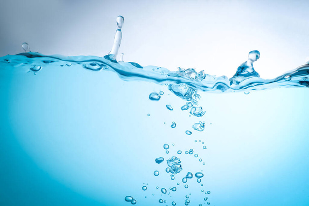 Поток воды создает всплеск и голубые волны под водой, и пузырьки естественным образом вытекают на поверхность. с копировальным местом - Фото, изображение