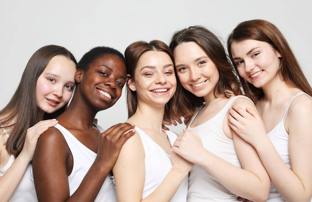 group of five young women friends of different nationalities hugging and smiling together - Foto, Imagem