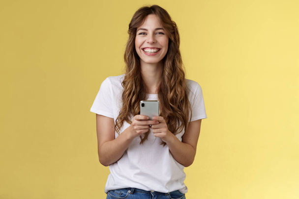 Iloinen huoleton onnellinen vilkas tyttö pidä älypuhelin käyttäen mahtava hauska sovellus pelaa viileä peli rentouttava odottaa ystävä puisto selailu sosiaalisen median avulla matkapuhelin näyttää kamera pirteä hymyillen - Valokuva, kuva