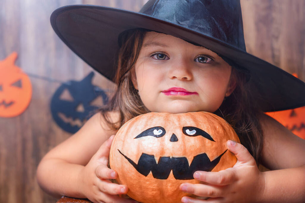 Portrait d'un enfant dans un chapeau de sorcière avec une citrouille pour Halloween - Photo, image