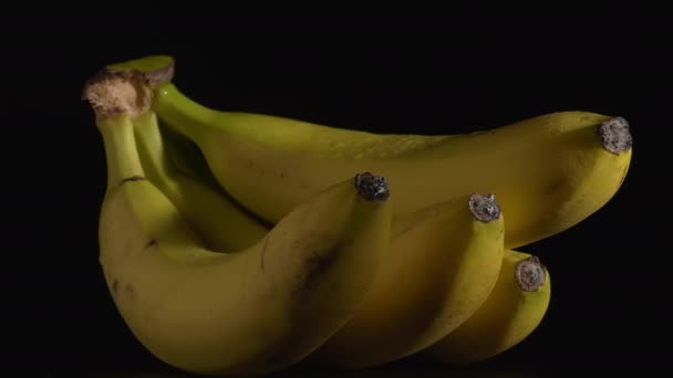 Zbliżenie mokrych obracających się bananów na czarnym tle. - Materiał filmowy, wideo