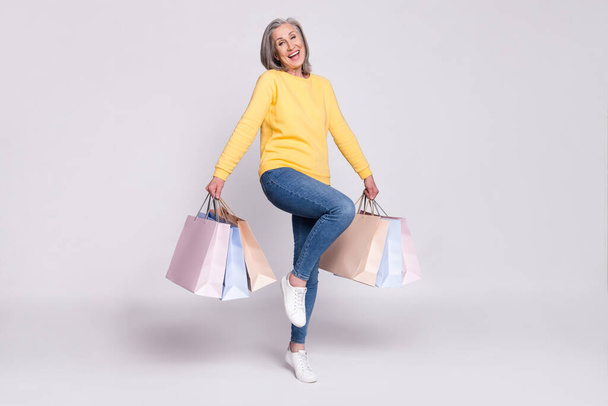 Full size photo of happy excited cheerful mature woman hold shopping bags isolated on grey color background - Foto, immagini