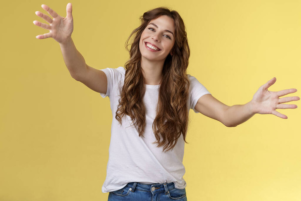 Wanna hold you tight. Romantic sincere gentle cute caucasian girl long beautiful curly hair tilt head lovely extend arms give cuddles wanna hug friend embracing dear guests yellow background - Photo, Image