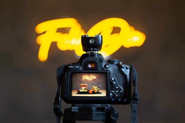 επαγγελματική κάμερα μπροστά από μια κίτρινη πινακίδα νέον - Φωτογραφία, εικόνα