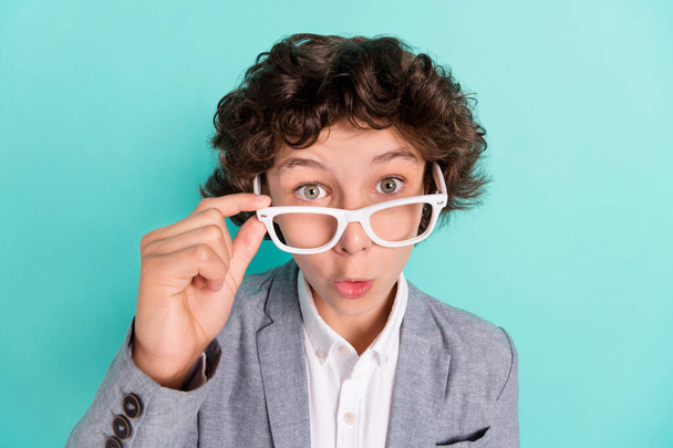 Photo of adorable impressed school boy wear grey jacket arm spectacles big eyes isolated turquoise color background - Foto, Imagem