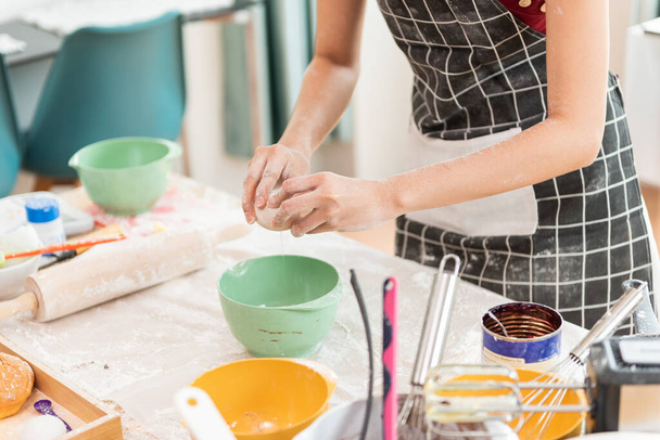Happy woman in the kitchen. Woman preparing the egg in bowl, bake cookies. - Foto, Bild