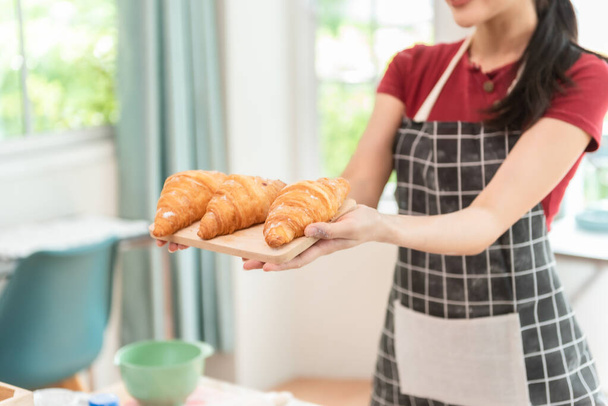 Пекарь женщина представляет хлеб на борту в пекарне, гордо глядя в камеру. - Фото, изображение