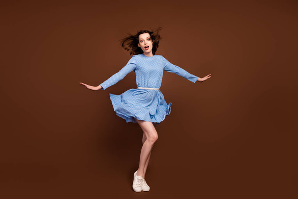 Full size photo of young attractive girl wind blow air hold arms isolated over brown color background - Photo, image